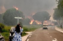 Eine Frau macht ein Foto von einem Waldbrand, der zur Evakuierung von mehr als 3.000 Menschen von nahe gelegenen Campingplätzen in Saint-Andre geführt hat.