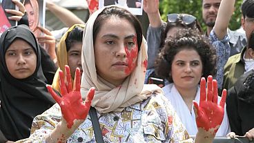 Une femme afghane le visage peint en rouge