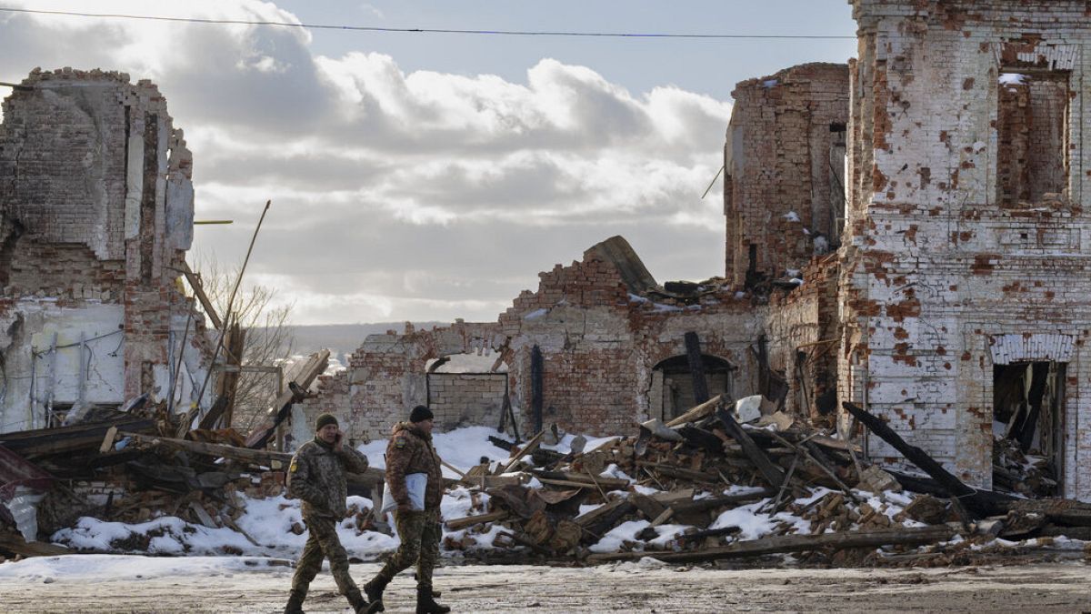 Ukrainian servicemen walk by a building destroyed by a Russian strike in Kupiansk, Ukraine, Monday, Feb. 20, 2023. 