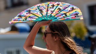 Une femme se protège du soleil à l'aide d'un ventilateur à main à Madrid, Espagne, juillet 2023\. 