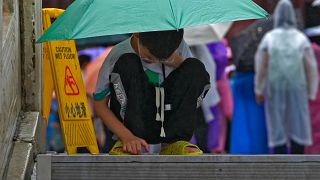 طفل صيني في بكين يقبع يتصفح هاتفه الذكي تحت مظلة