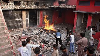 Fiatalok nézik a muszlimok által megrongált és felgyújtott egyik templomot