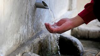 Un hombre toma agua potable de una fuente en Sidi Bou Said, al norte de Túnez.