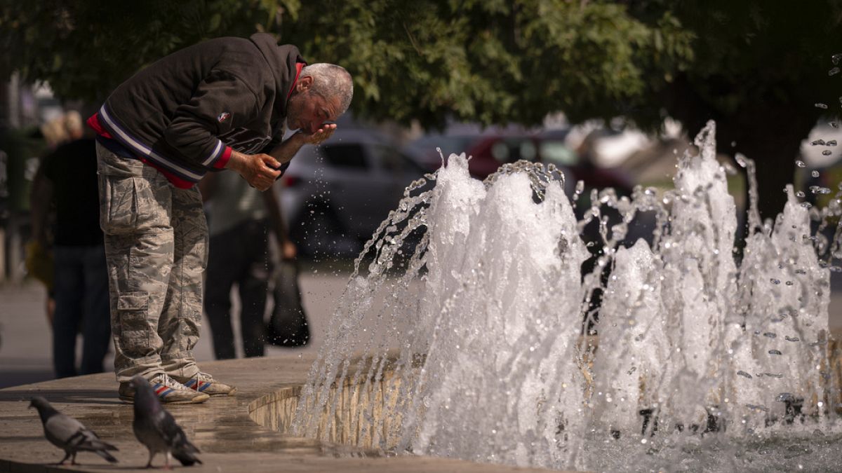 Un hombre se refresca en una fuente.