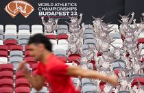 Ein Athlet läuft im Stadion vorbei an den offiziellen Maskottchen der diesjährigen Leichtathletik-WM in Budapest