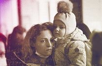 A woman holds her daughter as they try to get on a train at the Kyiv station, 4 March 2022