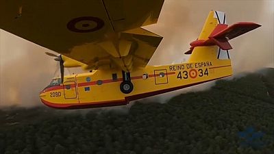 Ein Löschflugzeug fliegt über brennende Wälder auf Teneriffa