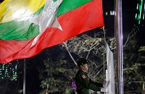 A Myanmar soldier hoists a national flag in Yangon.