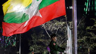 A Myanmar soldier hoists a national flag in Yangon.