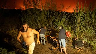 Los residentes locales tratan de limpiar el bosque para evitar que las llamas como el fuego avanza en La Orotava en Tenerife, Islas Canarias, España el sábado, 19 de agosto 2023.