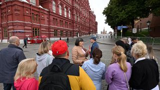  سياح يستمعون إلى مرشد سياحي بالقرب من الميدان الأحمر في موسكو، روسيا.