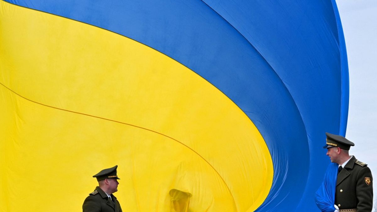 FILE - Ukrainian servicemen hold a huge national flag  near Kyiv, on March 31, 2023.
