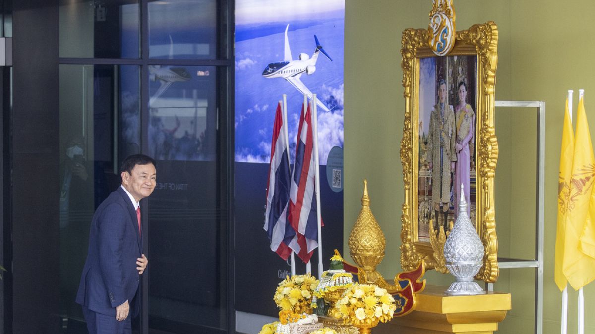 رئيس وزراء تايلاند السابق ثاكسين شيناواترا يقف أمام صورة للملك ماها فاجيرالونجكورن عند وصوله إلى مطار دون مويانغ في بانكوك، تايلاند، 22 أغسطس 2023.