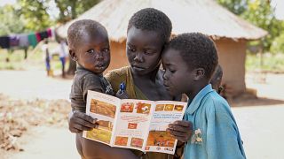 ثلاثة أطفال في السودان يقرؤون كتيبا