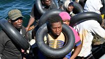 Migranten, die versuchen, nach Europa zu fliehen, werden am 10\. August auf dem Meer zwischen Tunesien und Italien von ihrem kleinen Boot auf ein Schiff der tunesischen Küstenwache umgeladen.