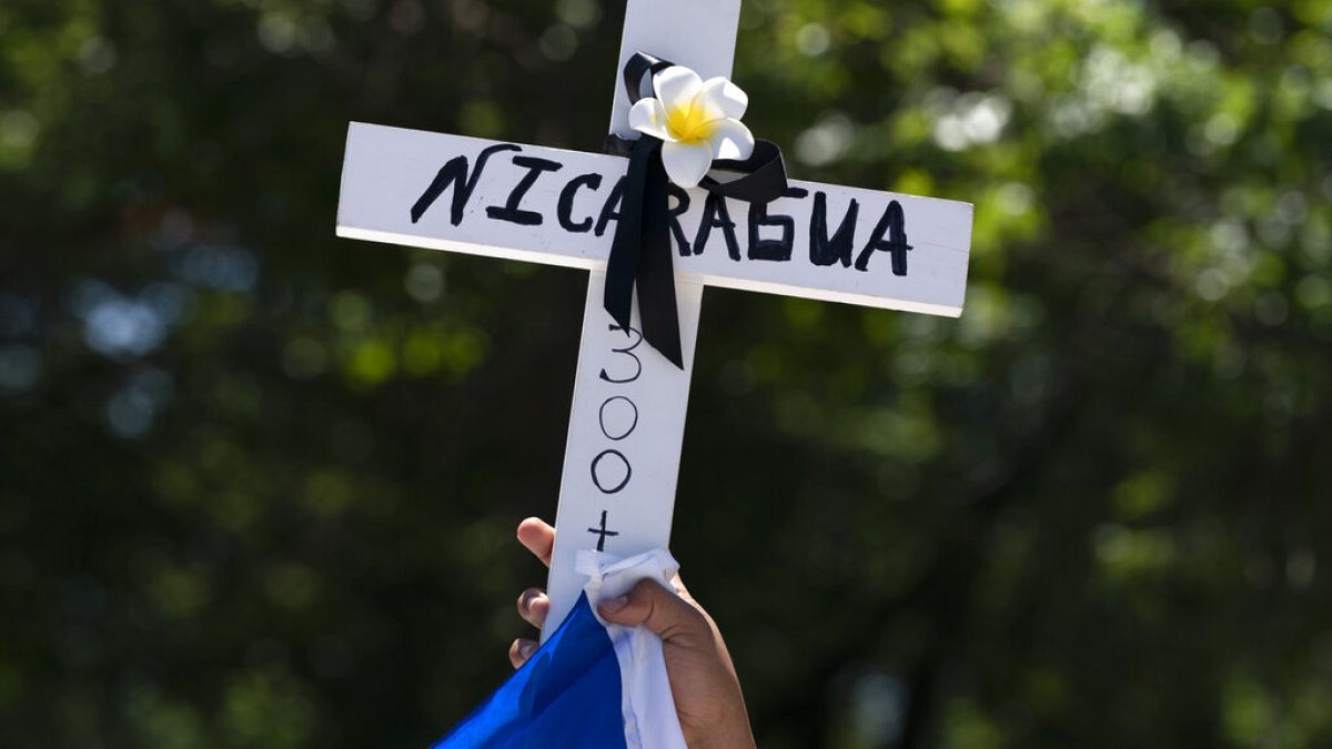 Manifestantes alzan una cruz con la palabra Nicaragua