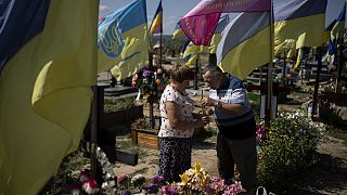 Kateryna and Oleh light a candle at son's grave, who died fighting in the war as Ukrainians mark Independence Day in Kharkiv, Ukraine, Thursday, Aug. 24, 2023