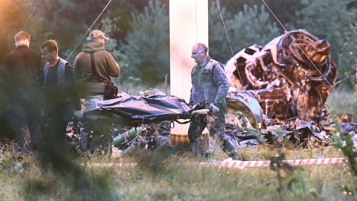 People carry a body bag away from the wreckage of a crashed jet near the village of Kuzhenkino, Russia. Wagner chief Yvgeny Prigozhin is thought to have been on board.
