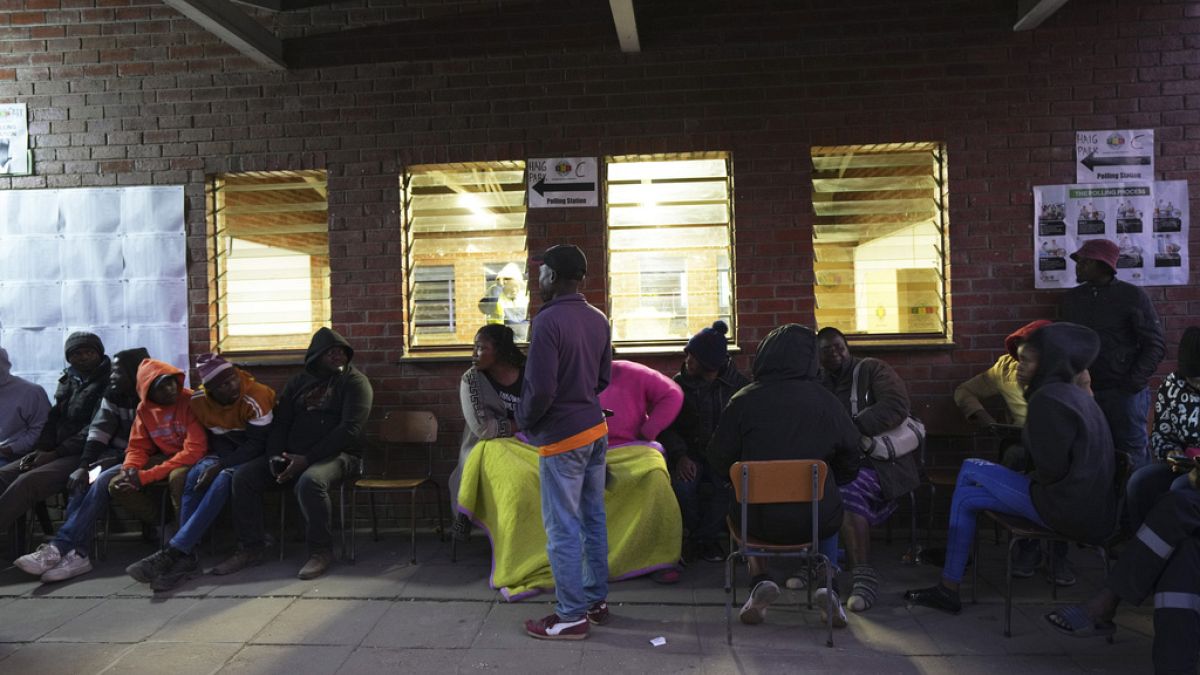People sit outside a polling station in Harare, Thursday, Aug. 24 ,2023. Voting is still underway in Zimbabwe. 