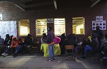 People sit outside a polling station in Harare, Thursday, Aug. 24 ,2023. Voting is still underway in Zimbabwe.