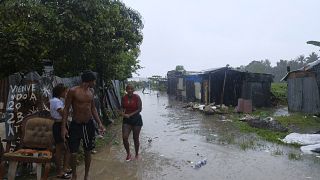 الناس يسيرون بين المنازل التي غمرتها أمطار العاصفة الاستوائية فرانكلين، على طول نهر أوزاما في حي غوالي في سانتو دومينغو، جمهورية الدومينيكان، الأربعاء 23 أغسطس 2023.