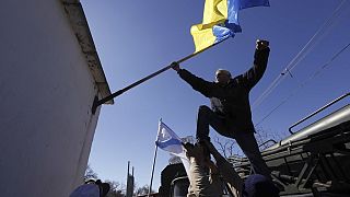 ΑΡΧΕΙΟ - Ένας άνδρας αφαιρεί μια ουκρανική σημαία μετά την κατάληψη της βάσης στη Novofedorivka της Κριμαίας, Σάββατο 22 Μαρτίου 2014.