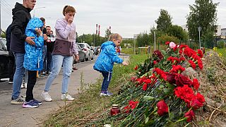 People with children lay flowers at an informal memorial next to the former 'PMC Wagner Centre' in St. Petersburg, Russia, Thursday, Aug. 24, 2023.
