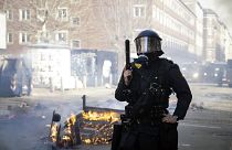 Danish police officers stand guard in April 2019 next to a fire lit by people who protested after someone tossed a copy of the Quran in the air in an immigrant neighbourhood