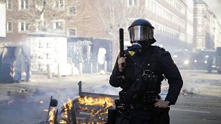 Agentes de policía daneses hacen guardia junto a un fuego encendido por personas que protestaban en un barrio de inmigrantes en Copenhague, el domingo 14 de abril de 2019.