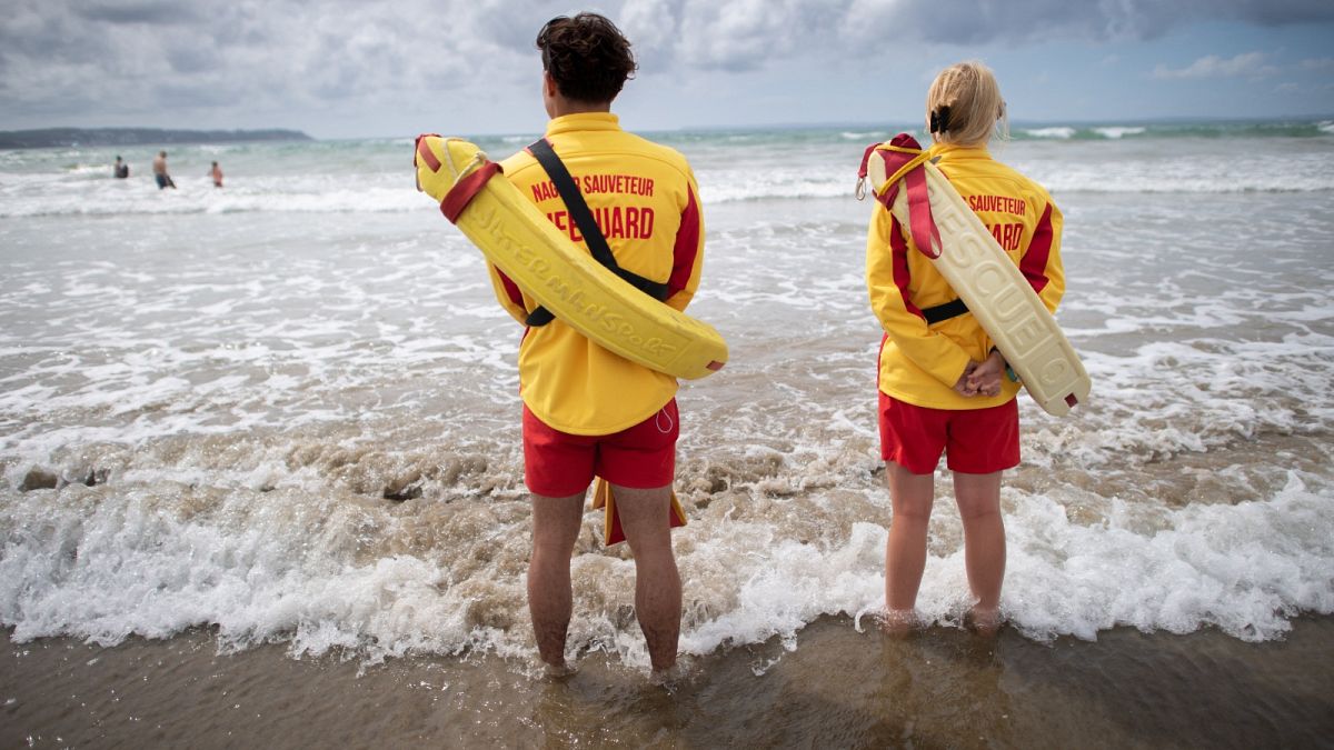 فريق الإنقاذ في SDIS 29، خدمة الإطفاء والإنقاذ في فينيستير، يقفون وهم ينظرون إلى الشاطئ في بلونيفيز بورزاي، غرب فرنسا، في 9 يوليو 2023.