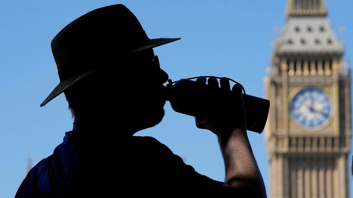 A tourist takes a refreshing drink opposite Big Ben in London, August 2022.