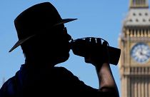 A tourist takes a refreshing drink opposite Big Ben in London, August 2022.