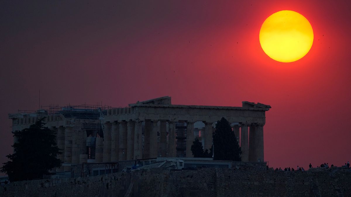 Smoke from a wildfire on the outskirts of Athens covers the sun as it sets over the Parthenon atop the ancient Acropolis.