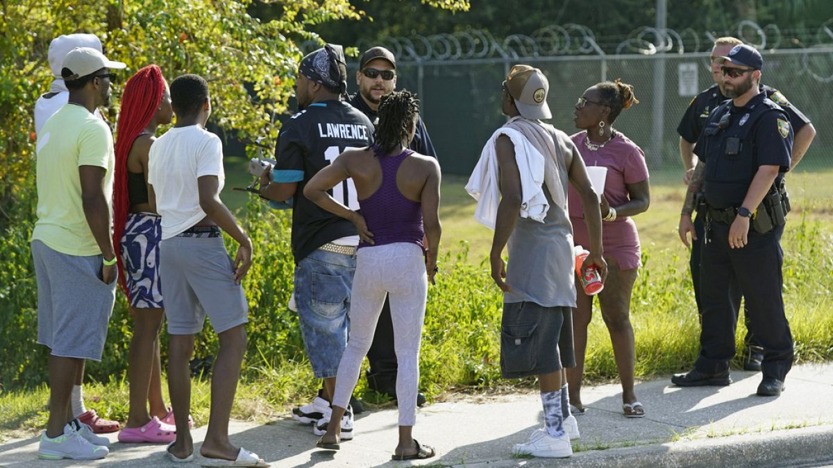 Residents talk with Jacksonville police officers near the scene of a mass shooting at a Dollar General store, Saturday, Aug. 26, 2023, in Jacksonville, Florida, US 
