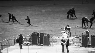 Policemen clear the field of enthusiastic fans as The Beatles perform on a bandstand in Candlestick Park, San Francisco