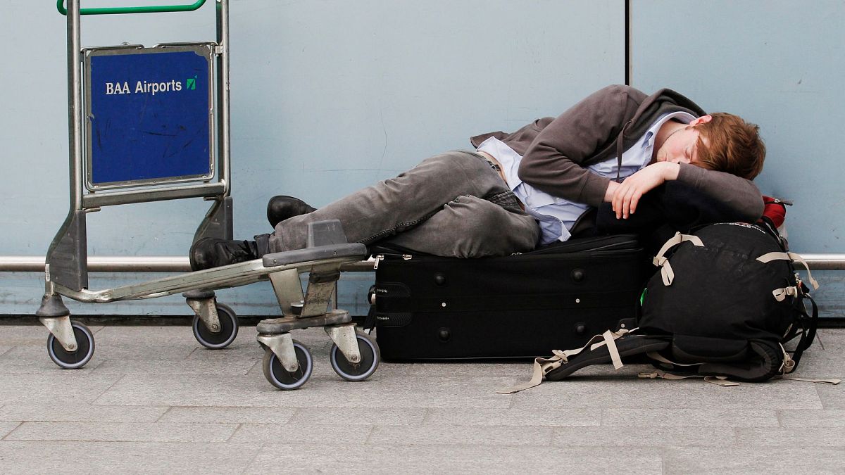 ARCHIVO - Un viajero descansa con su equipaje mientras se retrasan y cancelan vuelos en el aeropuerto de Heathrow, en Londres, 17 de mayo de 2010.