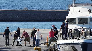 Des gardes-côtes grecs débarquent des migrants naufragés, dans le port de Mytilène, sur l'île de Lesbos, dimanche.