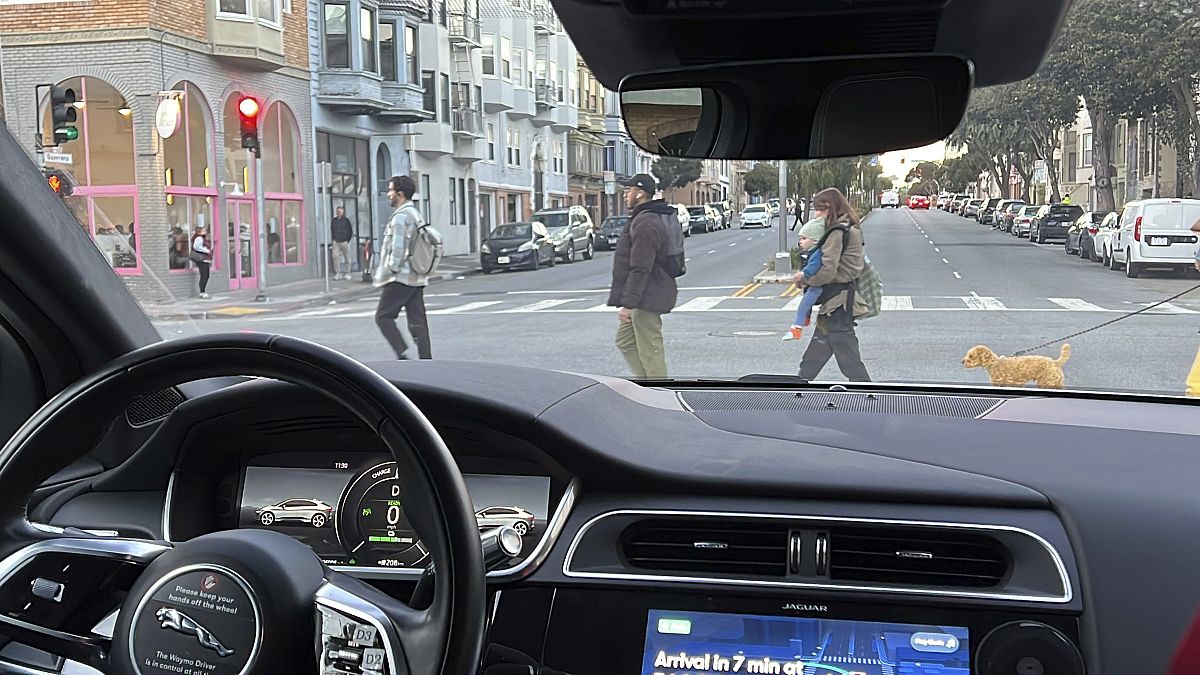 Un taxi sin conductor de Waymo se detiene en un semáforo mientras los peatones cruzan la calle durante un viaje de prueba en San Francisco, el 15 de febrero de 2023.
