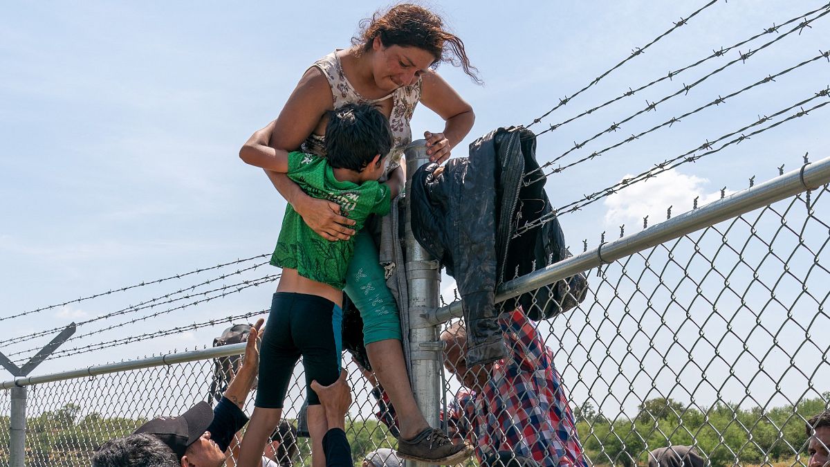 أم مهاجرة تساعد ابنها لعبور سياج شائك إلى الولايات المتحدة الأمريكية 