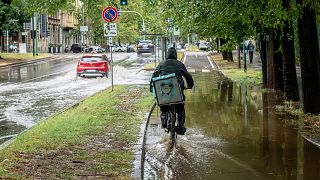 Un cycliste descend une rue inondée dans le quartier Sempione de Milan, Italie, lundi 28 août 2023.