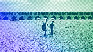 A woman and a boy walk on the dried up riverbed of the Zayandeh Roud river that no longer runs in Isfahan, July 2018