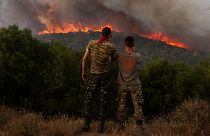 Dois homens assistem às chamas que lavram na região grega de Alexandrópolis