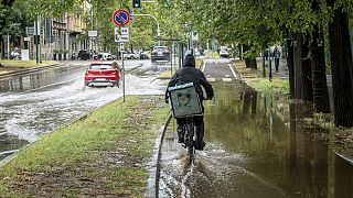 Un ciclista recorre una calle inundada en la zona de Sempione de Milán, Italia, el lunes 28 de agosto de 2023.