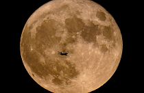 FILE - A plane passes in front of a supermoon, July 13, 2022