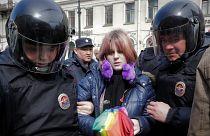 Egy szivárványos esernyőt tartó melegjogi aktivistát őrizetbe vesznek a rendőrök egy tüntetésen Szentpétervár belvárosában 2017-ben.