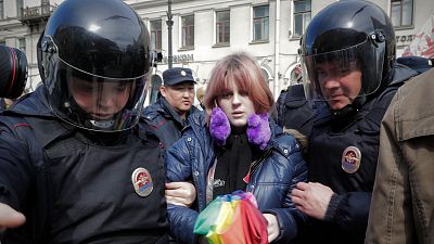 A gay rights activist holding a rainbow umbrella is detained by police during a rally in downtown St. Petersburg on 2017.