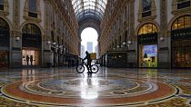 In this Nov. 6, 2020 file photo, a food delivery rider pushes his bicycle inside the Vittorio Emanuele shopping arcade in Milan, Italy.