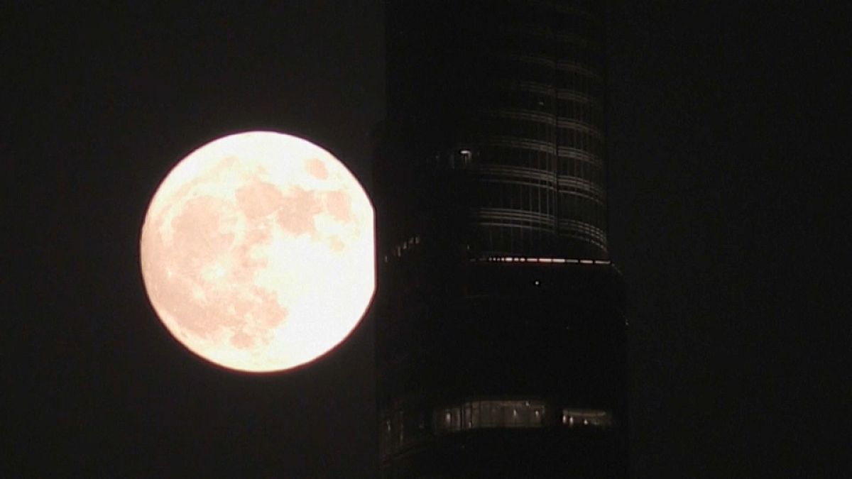 القمر الأزرق العملاق يضيء سماء دبي، فيما يظهر برج خليفة في الأفق