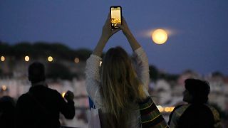 Une femme prend des photos de la super Lune bleue au-dessus de Lisbonne, au Portugal, mercredi 30 août 2023.