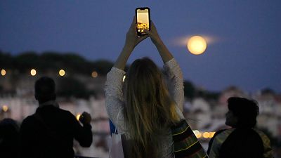 Une femme prend des photos de la super Lune bleue au-dessus de Lisbonne, au Portugal, mercredi 30 août 2023.